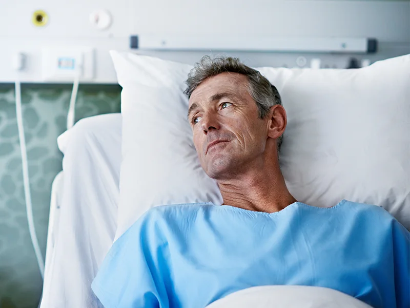 Man resting in hospital bed after bicep tendon surgery, representing early recovery period and post-operative care